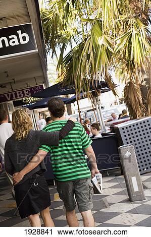 Stock Image - Couple Walking Near Sidewalk Cafe In St Kilda, Melbourne, Australia. Fotosearch