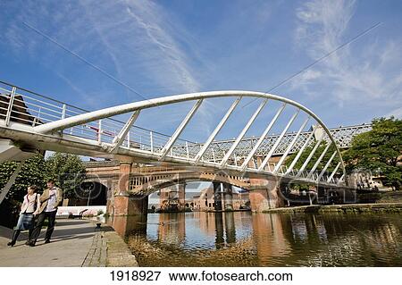 Couple walking under bridge by canal, Castlefield, Manchester, England View Large Photo Image Stock Photo - Couple walking under bridge by canal, Castlefield, Manchester, England. Fotosearch