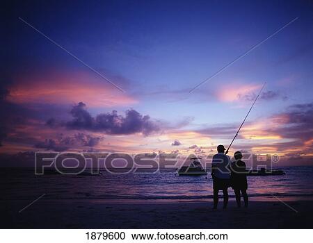 Stock Image - Couple With Fishing Rod Watching The Sunset. Fotosearch