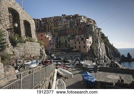 Stock Photo - Covered Boats On Land And Houses Along The Coast; Manarola, Liguria, Italy. Fotosearch
