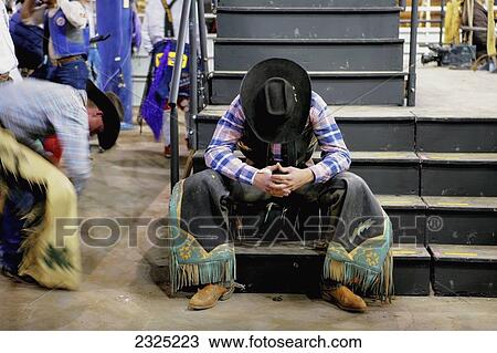 Stock Image - Cowboy Sitting On Stage Steps With Head Down; Alberta, Canada. Fotosearch