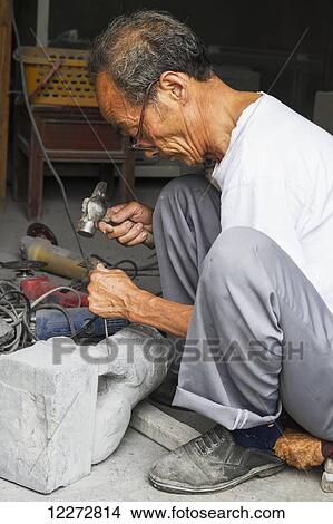 Picture - Craftsman carving a stone lion, Xidi, Anhui, China. Fotosearch