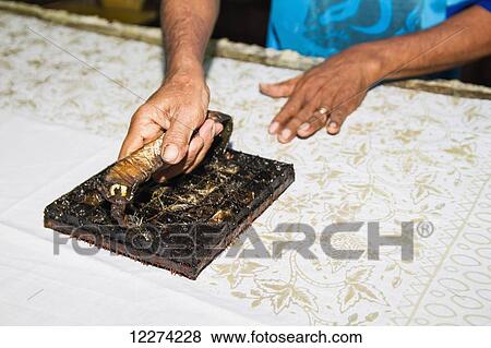 Stock Photo - Craftsman using a copper block stamp, called cap, to apply hot wax to a fabric in the production of printed batik at Gunawan Setiawan Batik Shop, Kampung Kauman, Surakarta (Solo), Central Java, Indonesia. Fotosearch