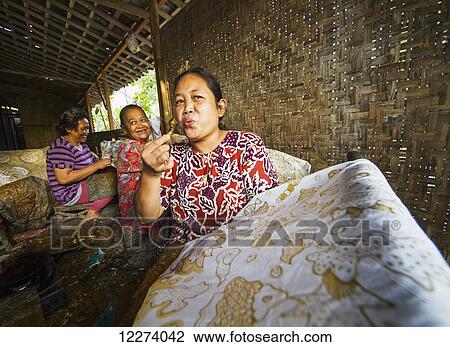 Craftswoman blowing a pen-like instrument, called canting, used to draw intricate patterns by applying hot wax to a fabric in the production of batik at Sarwidi's Batik workshop, Banyuripan-Bayat, Central Java, Indonesia View Large Photo Image Stock Image - Craftswoman blowing a pen-like instrument, called canting, used to draw intricate patterns by applying hot wax to a fabric in the production of batik at Sarwidi's Batik workshop, Banyuripan-Bayat, Central Java, Indonesia. Fotosearch
