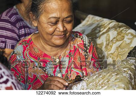Craftswoman drawing intricate patterns by using a pen-like instrument, called canting, to apply hot wax to a fabric in the production of batik at Sarwidi's Batik workshop, Banyuripan-Bayat, Central Java, Indonesia View Large Photo Image Stock Image - Craftswoman drawing intricate patterns by using a pen-like instrument, called canting, to apply hot wax to a fabric in the production of batik at Sarwidi's Batik workshop, Banyuripan-Bayat, Central Java, Indonesia. Fotosearch