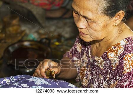 Craftswoman drawing intricate patterns by using a pen-like instrument, called canting, to apply hot wax to a fabric in the production of batik at Sarwidi's Batik workshop, Banyuripan-Bayat, Central Java, Indonesia View Large Photo Image Stock Image - Craftswoman drawing intricate patterns by using a pen-like instrument, called canting, to apply hot wax to a fabric in the production of batik at Sarwidi's Batik workshop, Banyuripan-Bayat, Central Java, Indonesia. Fotosearch