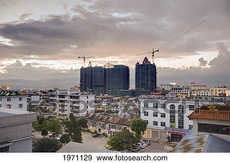Stock Photo - Cranes Working On Highrise Buildings With Clouds Overhead; Mingshi Yunnan China. Fotosearch