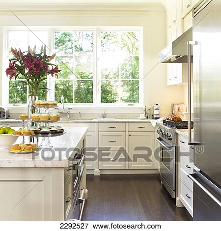 Stock Photo - Cream kitchen with cupcakes on cake tier and pink lilies; Victoria vancouver island british columbia canada. Fotosearch