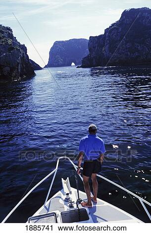 Stock Image - Crewman On Bow Getting Ready To Anchor In Cove. Fotosearch