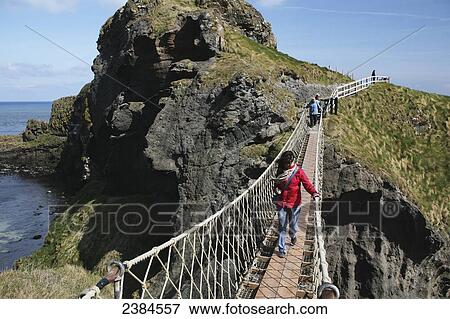 Crossing Carrick-a-Rede rope bridge, a suspension bridge which spans 20 metres from the mainland to the tiny Carrick Island; County Antrim, Ireland View Large Photo Image Stock Photo - Crossing Carrick-a-Rede rope bridge, a suspension bridge which spans 20 metres from the mainland to the tiny Carrick Island; County Antrim, Ireland. Fotosearch