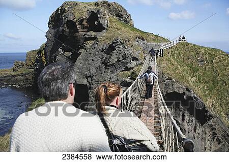 Crossing Carrick-a-Rede rope bridge, a suspension bridge which spans 20 metres from the mainland to the tiny Carrick Island; County Antrim, Ireland View Large Photo Image Stock Photo - Crossing Carrick-a-Rede rope bridge, a suspension bridge which spans 20 metres from the mainland to the tiny Carrick Island; County Antrim, Ireland. Fotosearch