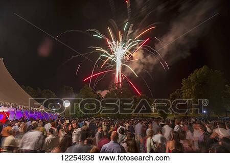 Stock Photo - Crowd of people watching fireworks while a couple take a self-portrait in the crowd; Lewisburg, Pennsylvania, United States of America. Fotosearch