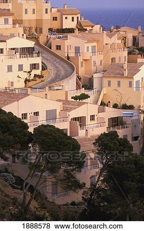Stock Photo - Curved Road Going Down Hilltop Village By Coastline. Fotosearch