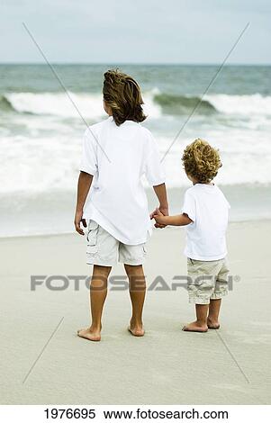 Cute Young Boys On The Beach, Looking At The Ocean Holding Hands. View Large Photo Image Stock Photography - Cute Young Boys On The Beach, Looking At The Ocean Holding Hands.. Fotosearch