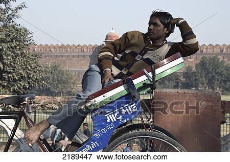 Stock Photo - Cycle Walla Resting On His Bike With The Red Fort In The Background, Delhi, Uttar Pradesh, India. Fotosearch