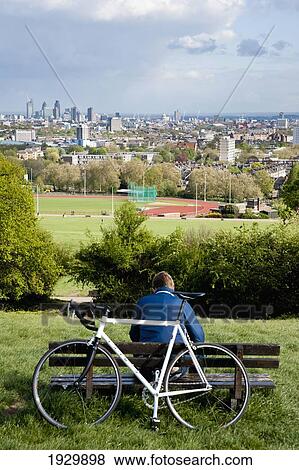 Stock Photo - Cyclist Enjoying The View Of London From Parliament Hill In Hamstead Heath, London, Uk. Fotosearch