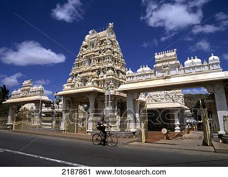 Stock Image - Cyclist on a street going past an ornate white building. Fotosearch