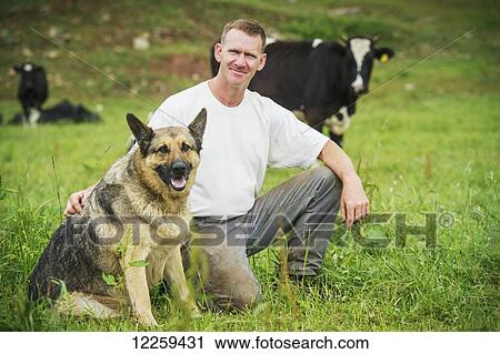 Stock Image - Dairy farmer with his German Shepard dog in Garrett County; Maryland, United States of America. Fotosearch