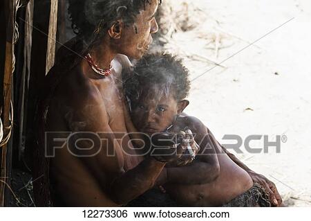 Stock Photograph - Dani woman holding a boy, Obia Village, Baliem Valley, Central Highlands of Western New Guinea, Papua, Indonesia. Fotosearch