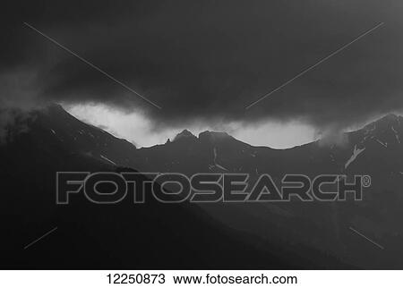Stock Image - Dark storm clouds over a mountain range; Austria. Fotosearch