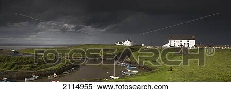 Stock Photography - Dark Storm Clouds Over A Village On The Coast; Seaton Sluice Northumberland England. Fotosearch