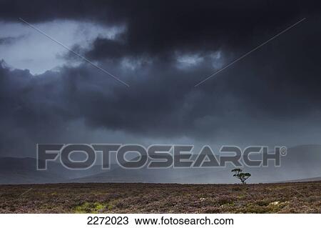 Stock Image - Dark Storm Clouds With Rain Streaks And Mountains In The Distance; Highlands Scotland. Fotosearch