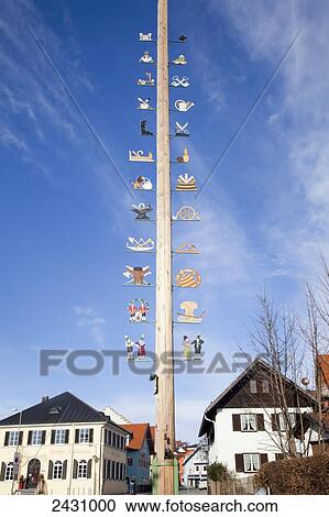 Stock Image - Decorative images mounted up a wooden post with houses in the background; Murnau, Bavaria, Germany. Fotosearch