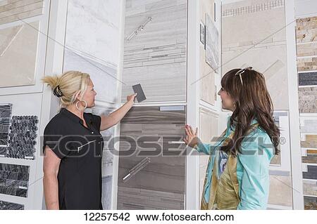 Stock Image - Design consultant and interior designer selecting tiles in showroom of tile store; Edmonton, Alberta, Canada. Fotosearch