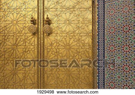 Stock Photo - Detail of a gold pattern on a set of doors beside a colourful design on a wall; Fez, Morocco. Fotosearch