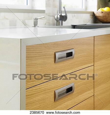 Stock Image - Detail of edge grain oak cabinets with modern stainless steel pulls; Victoria, Vancouver Island, British Columbia. Fotosearch