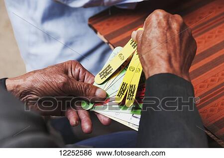 Stock Photograph - Detail of hands of a old man playing traditional Chinese cards; Yongding, Fujian province, China. Fotosearch