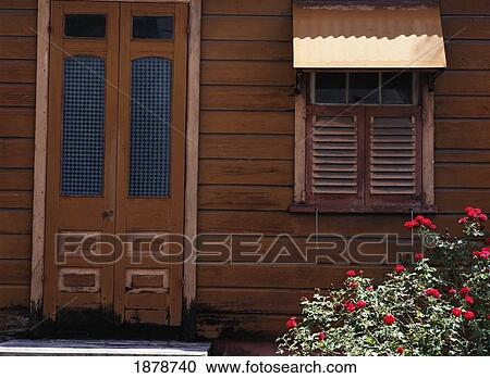 Stock Image - Detail Of Old Chattel House With Rose Bush In Front. Fotosearch