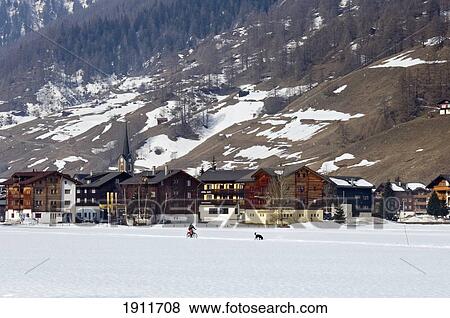 Stock Photo - Distant View Of Village And Cyclist With Dog, Ulrichen, Goms Valley, Switzerland. Fotosearch