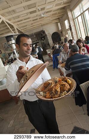 Stock Photo - Djerba Tunisia, A waiter displays typical seafood tajine dish served at Restaurant Haroun. Fishing port La Marsa; Houmt Souq. Fotosearch