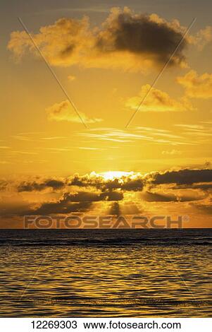 Dramatic orange sunrise with light reflecting in ocean and sun rays coming through clouds; Akumal, Quintana Roo, Mexico View Large Photo Image Stock Image - Dramatic orange sunrise with light reflecting in ocean and sun rays coming through clouds; Akumal, Quintana Roo, Mexico. Fotosearch