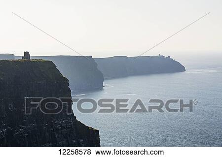 Stock Photo - Dramatic rock cliffs along shoreline and castle turret; Liscannor, County Clare, Ireland. Fotosearch