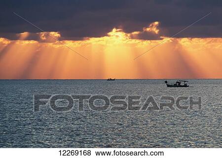 Stock Photo - Dramatic sky with sun rays filtering down out of the storm clouds over the horizon; Paphos, Cyprus. Fotosearch