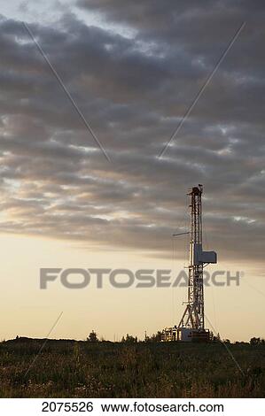 Stock Photograph - Drilling Rig With Dramatic Clouds At Sunrise; Alberta Canada. Fotosearch