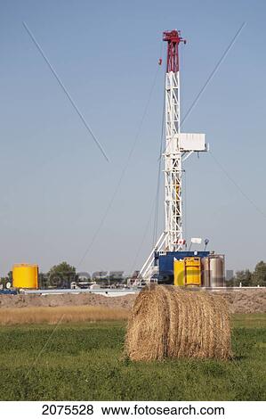 Drilling Rig With Round Hay Bale In The Foreground And Blue Sky; Alberta Canada View Large Photo Image Stock Photo - Drilling Rig With Round Hay Bale In The Foreground And Blue Sky; Alberta Canada. Fotosearch