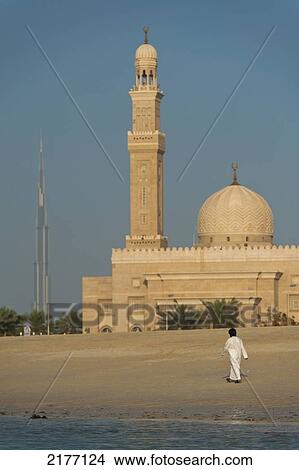 Dubai, Uaeman Walking Along Beach In Front Of Small Mosque And The Burj Khalifa In The Distance View Large Photo Image Picture - Dubai, Uaeman Walking Along Beach In Front Of Small Mosque And The Burj Khalifa In The Distance. Fotosearch
