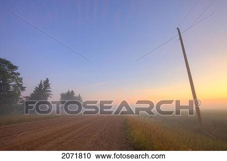 Stock Image - Early Morning On A Fog Covered Gravel Road, North Of Edmonton, Alberta. Fotosearch