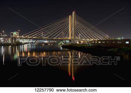 Stock Image - East 21th street suspension bridge and reflection over the Foss Waterway at night, Tacoma, Washington, USA. Fotosearch