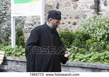 Stock Image - Eastern Orthodox priest checking his messages, Rila Monastery, Blagoevgrad, Bulgaria. Fotosearch