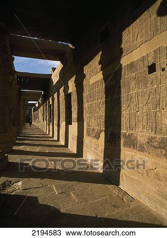 Stock Image - Egypt, Aswan, woman in distance; Philae Island, Temple of Isis, West Colonnade covered in reliefs and hieroglyphs. Fotosearch