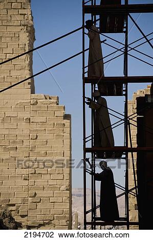 Stock Image - Egypt, Precinct of Amun; Luxor, Silhouette of men putting up scaffolding on Karnak Temple. Fotosearch