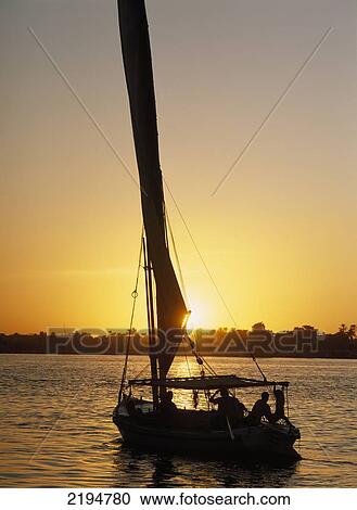 Stock Image - Egypt, Silhouette of felucca on River Nile at dusk; Luxor. Fotosearch