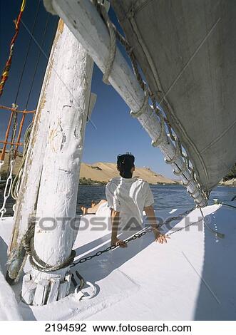 Stock Image - Egypt, Woman sitting on bow of felucca on River Nile; Aswan. Fotosearch