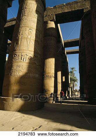 Stock Image - Egypt, Woman walking through Great Hypostyle Hall of Temple of Amun; Karnak; Luxor. Fotosearch