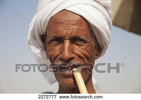 Stock Photo - Egyptian man smoking local reed pipe; west bank luxor upper egypt. Fotosearch