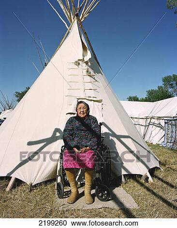 Stock Image - Elderly Crow Woman Dressed In Traditional Garment In Front Of Her Family Tepee During Annual Crow Fair (August), The Largest Native American Festival In The Usa. The Crow (Apsaaloke, Apsaroke Or Absaroke) Live In The Crow Reservation (Montana, Usa).. Fotosearch